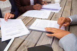 business people sitting at a wooden table reviewing business contracts