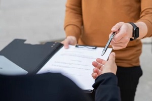 man taking pen to sign papers